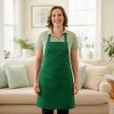 Cleaning professional in a green apron standing in a sunlit Columbia living room